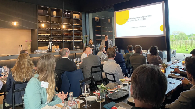 Speaker presenting to an audience during a dinner, with "90% content AI generated by 2025" on screen.