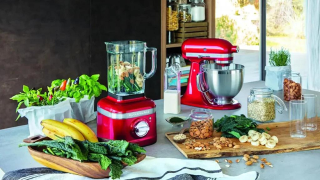 Red KitchenAid blender and stand mixer on a counter with smoothie ingredients and fresh produce.