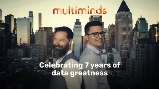 Two men, Multiminds data greatnes, smiling against a city skyline, celebrating 7 years.