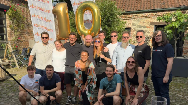 Team celebrates 10-year anniversary with golden balloons and banners outdoors.